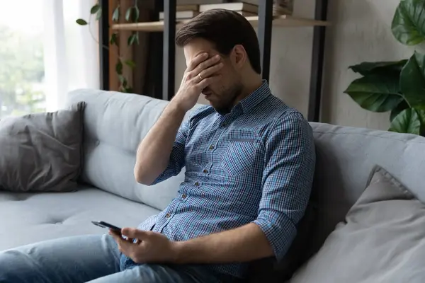 Triste hombre sostiene teléfono inteligente que sufre de relaciones romper mensaje — Foto de Stock