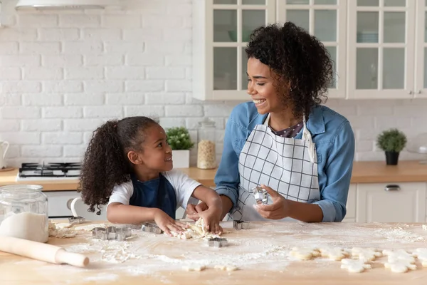 Schöne afrikanische Mutter und ihre Tochter kochen Kekse in der Küche — Stockfoto