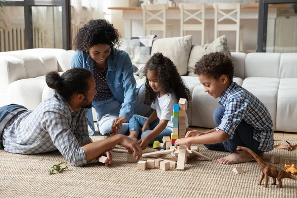 Afrikanische Kinder und Eltern spielen zu Hause gemeinsam Holzspielzeug — Stockfoto