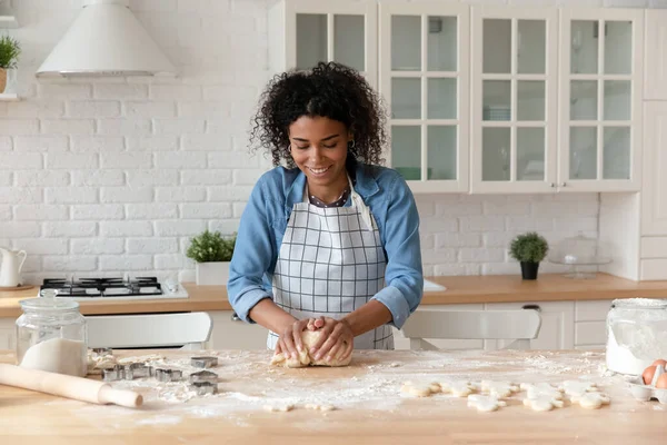 Atractiva ama de casa africana amasando masa, preparar pasteles en la cocina —  Fotos de Stock