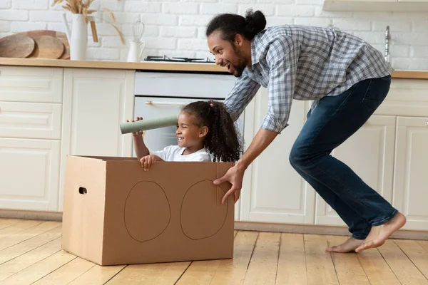 African father rides his little daughter in carton box — Stock Photo, Image