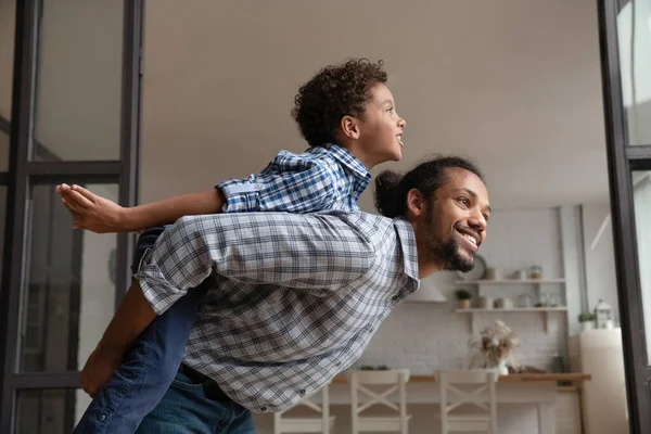 Afrikanischer Vater reitet seinen kleinen Sohn auf dem Rücken — Stockfoto