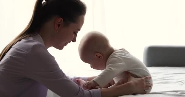 Szczęśliwego tysiąclecia matka bawić się z uroczym dzieckiem uczy się siedzieć — Wideo stockowe