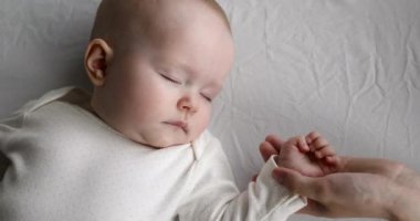 Anne huzurlu uykuyu koruyor. Sevilen bebeğin minik elini okşuyor.