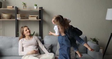 Gülümseyen anne bebek bekliyor, baba kızıyla oynuyor.