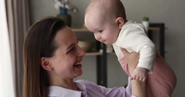 Millennial anne kucağında bebekle oyun oynuyor.