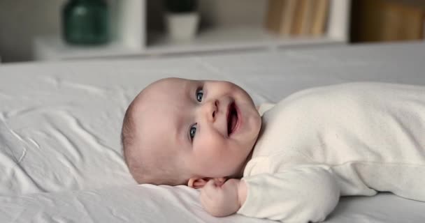 Portret schattige baby liggend op bed lachend kijkend naar camera — Stockvideo