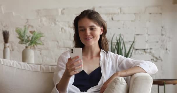 Kobieta patrzy na ekran komórkowy prowadzić rozmowę poprzez wideokonferencje — Wideo stockowe