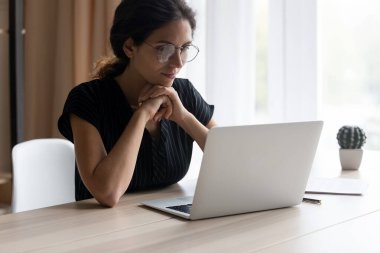 Genç Latin kadın evde bilgisayarda çalışıyor.