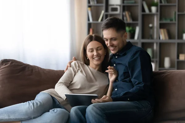 Ευτυχισμένο χαλαρό νεαρό οικογενειακό ζευγάρι που χρησιμοποιεί ψηφιακό tablet υπολογιστή. — Φωτογραφία Αρχείου