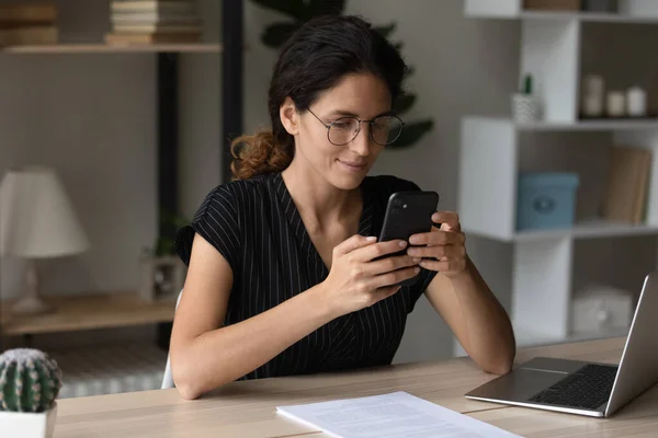 Smiling Latin woman use smartphone communicating online — Stock Photo, Image
