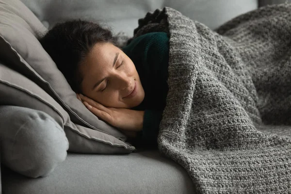 落ち着いたヒスパニック系の女性は毛布の下でソファにリラックス — ストック写真