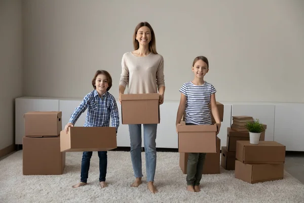 Familia feliz posando en un nuevo hogar con cajas en las manos. — Foto de Stock