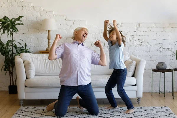 Glad gammal man dansar med barnbarn hemma. — Stockfoto