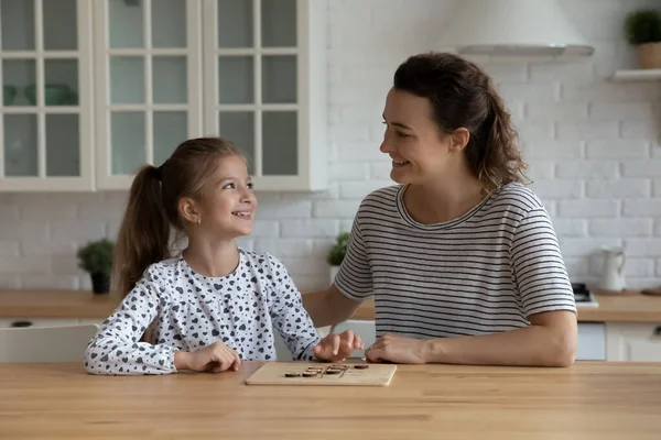 Leende omtänksam mor och 9s dotter spelar trä brädspel — Stockfoto