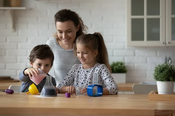 Happy loving mother and kids playing with toy laboratory — 图库照片