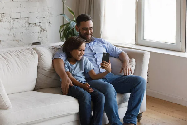 Joyeux adolescent enfant utilisant un téléphone portable avec jeune père. — Photo