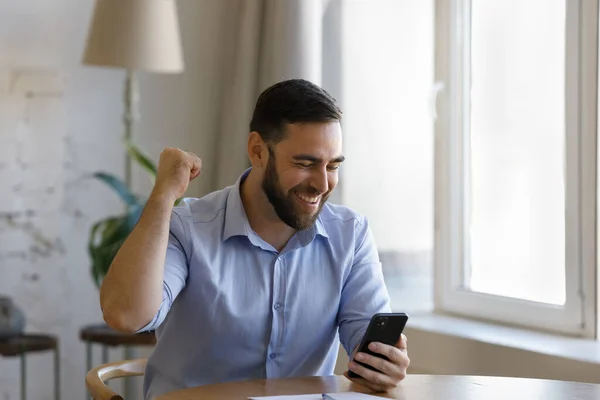 Glad uppriktig ung affärsman firar att få fantastiska nyheter på mobiltelefon. — Stockfoto