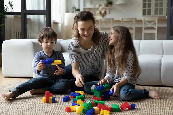 Happy mother with son and daughter playing on warm floor — 图库照片