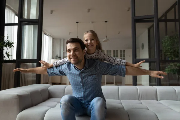 Happy dreamy Caucasian father piggy backing 8s daughter, pretending flying — Stock Photo, Image