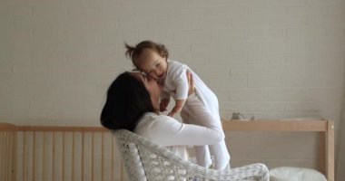 Genç anne, sandalyede otur ve küçük kızı kaldır.