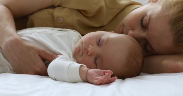 Trött tusenårig mor sover på skön säng tillsammans med spädbarn — Stockvideo