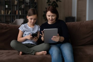 Yaşlı büyükanne torunuyla kanepede oturur.