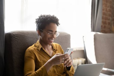 Akıllı telefon kullanan mutlu, Afro-Amerikan bir kadın..