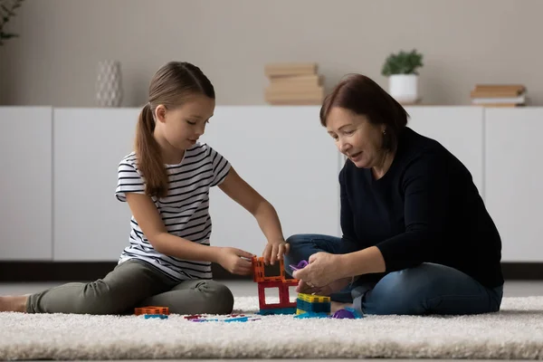 Feliz niña preadolescente jugar con anciana abuelita construir juguete torre —  Fotos de Stock