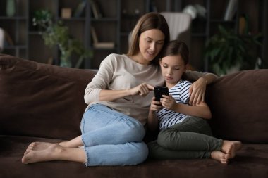 İlgili milenyum dişisi küçük kızına cep telefonu uygulamaları kullanmayı öğretiyor.