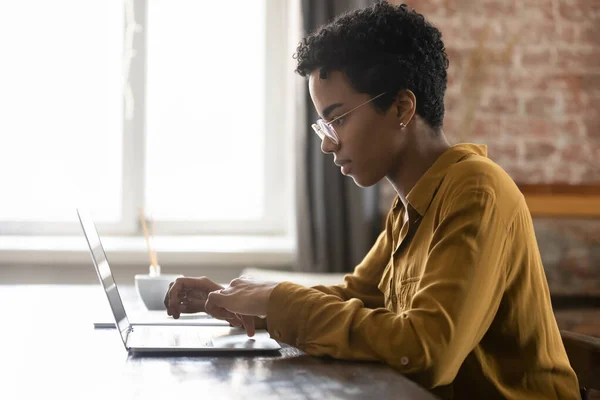 Fokuserad ung afrikansk amerikansk affärskvinna arbetar på dator. — Stockfoto