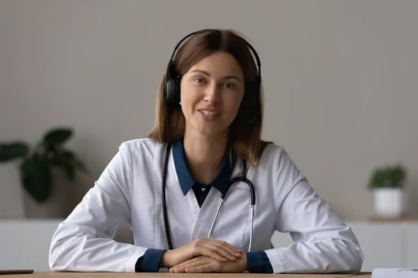 Female doctor in headset talk to patient from pc screen — Stockfoto