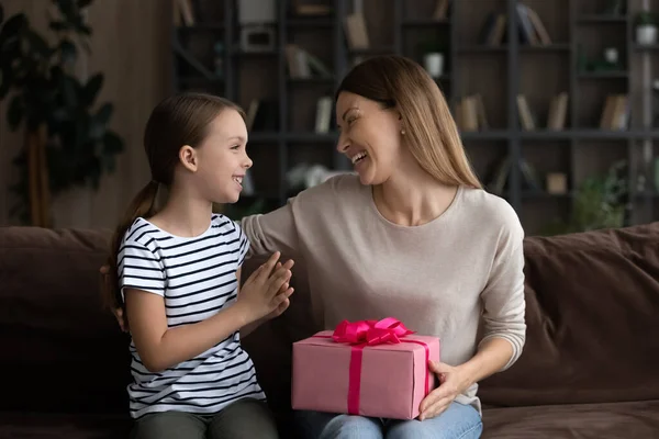 Chica sonriente presentando regalo a mamá agradecida en el Día de la Mujer — Foto de Stock
