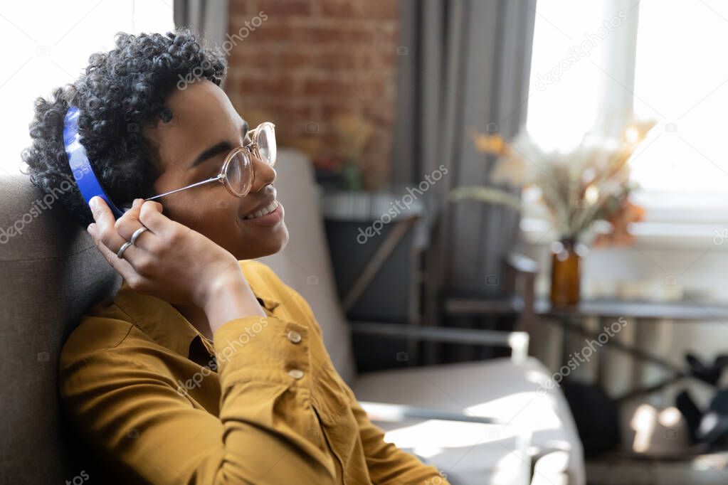 Happy young African American woman listening music in headphones.