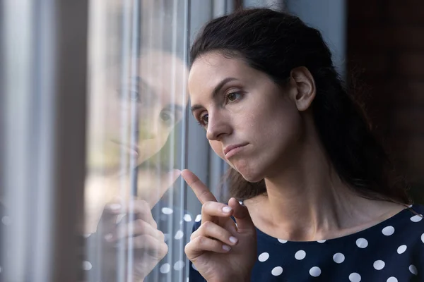 Frustrato infelice giovane donna ispanica guardando fuori dalla finestra. — Foto Stock