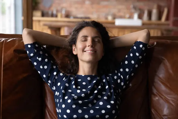 Tranquillo felice giovane donna ispanica che riposa su un accogliente divano. — Foto Stock