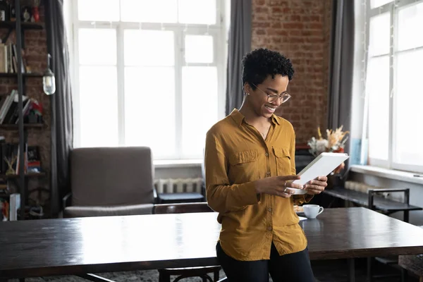 Happy young African American woman using digital tablet.