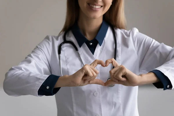 Primer plano de la joven doctora haciendo corazón de dedos — Foto de Stock