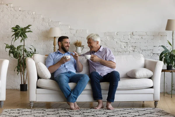 Unbekümmert entspannter junger Mann und alter Vater im Gespräch zu Hause. — Stockfoto