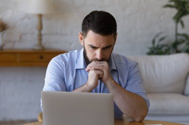 Bilgisayar ekranına bakan stresli genç iş adamı.