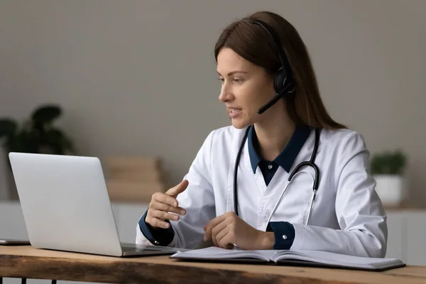 Zelfverzekerde vrouwelijke arts zitten door laptop raadplegen patiënt door videocall — Stockfoto