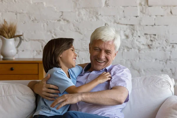 Happy laughing preteen kid boy tickling old grandfather. — Stock Photo, Image