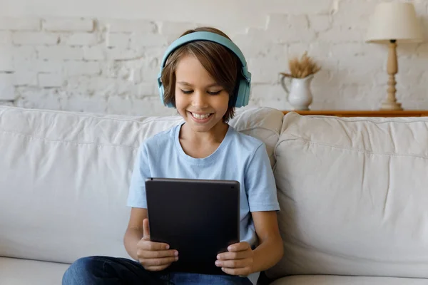 Joyful 12s tiener jongen in hoofdtelefoon met behulp van tablet. — Stockfoto