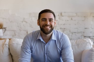 Kanepede oturan gülümseyen genç adamın portresi.