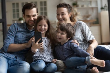 Mutlu ebeveynler ve iki çocuk akıllı telefonla eğleniyor.