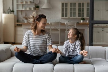 Mutlu anne ve küçük kızı meditasyon yapıyor, birlikte yoga yapıyorlar.
