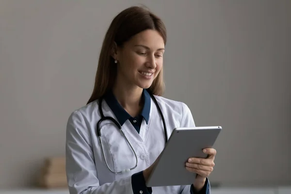 Счастливая современная женщина-медик работает в Интернете на планшете — стоковое фото