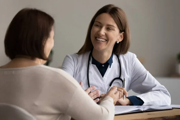 Smiling female gp listen to elderly woman visitor on meeting — Stock Photo, Image