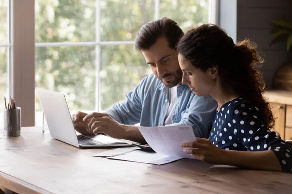 Concentrated young couple managing household budget at home. — 图库照片