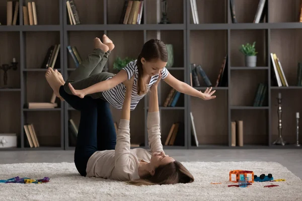 Enérgico milenar mãe levantar até ar tween adotivo filha — Fotografia de Stock